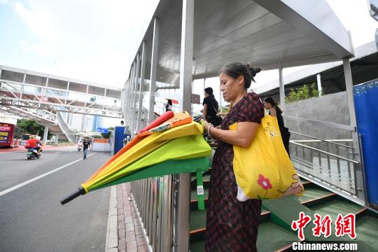 图为一市民尝试取用共享雨伞。　俞靖 摄